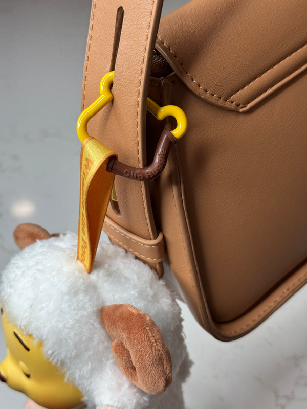 Plush charm on a handbag strap with a Clip Huggie
